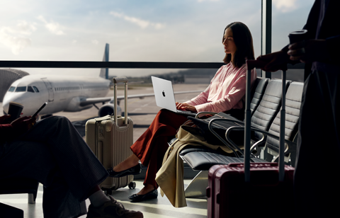 An employee types on a 14-inch MacBook Pro in Silver while unplugged, as they wait for their flight at an airport gate