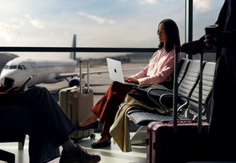 An employee types on a 14-inch MacBook Pro in Silver while unplugged, as they wait for their flight at an airport gate