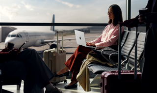 An employee types on a 14-inch MacBook Pro in Silver while unplugged, as they wait for their flight at an airport gate