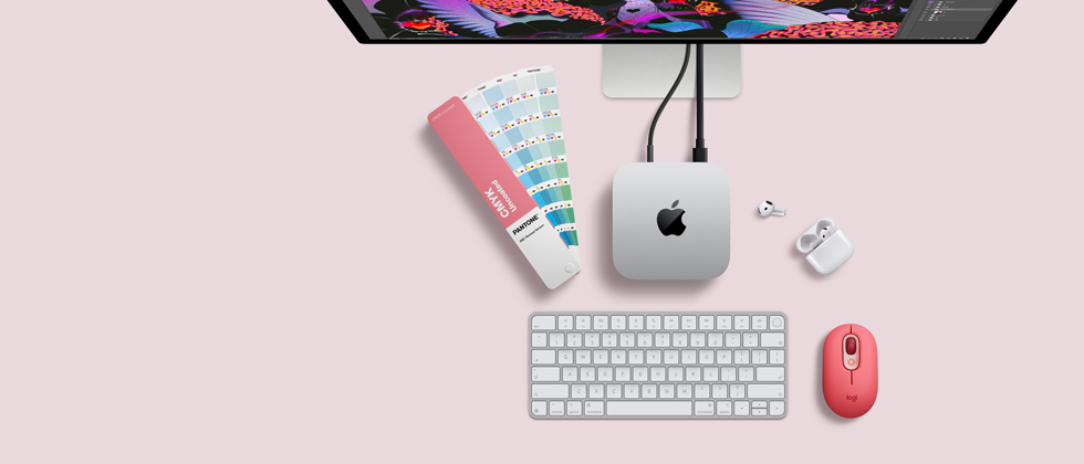 Mac mini, top, silver aluminum, rounded corners, glossy black Apple logo centered, connected by cord, Studio Display partially visible on top, AirPods 4, open, Pantone color swatches, Magic Keyboard, and mouse