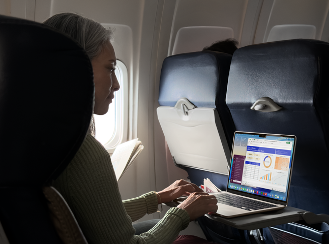 A person using a MacBook Air while sitting on an airplane, to demonstrate the device's long battery life