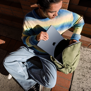 Front view of a person placing a closed 15-inch MacBook Air into a bag