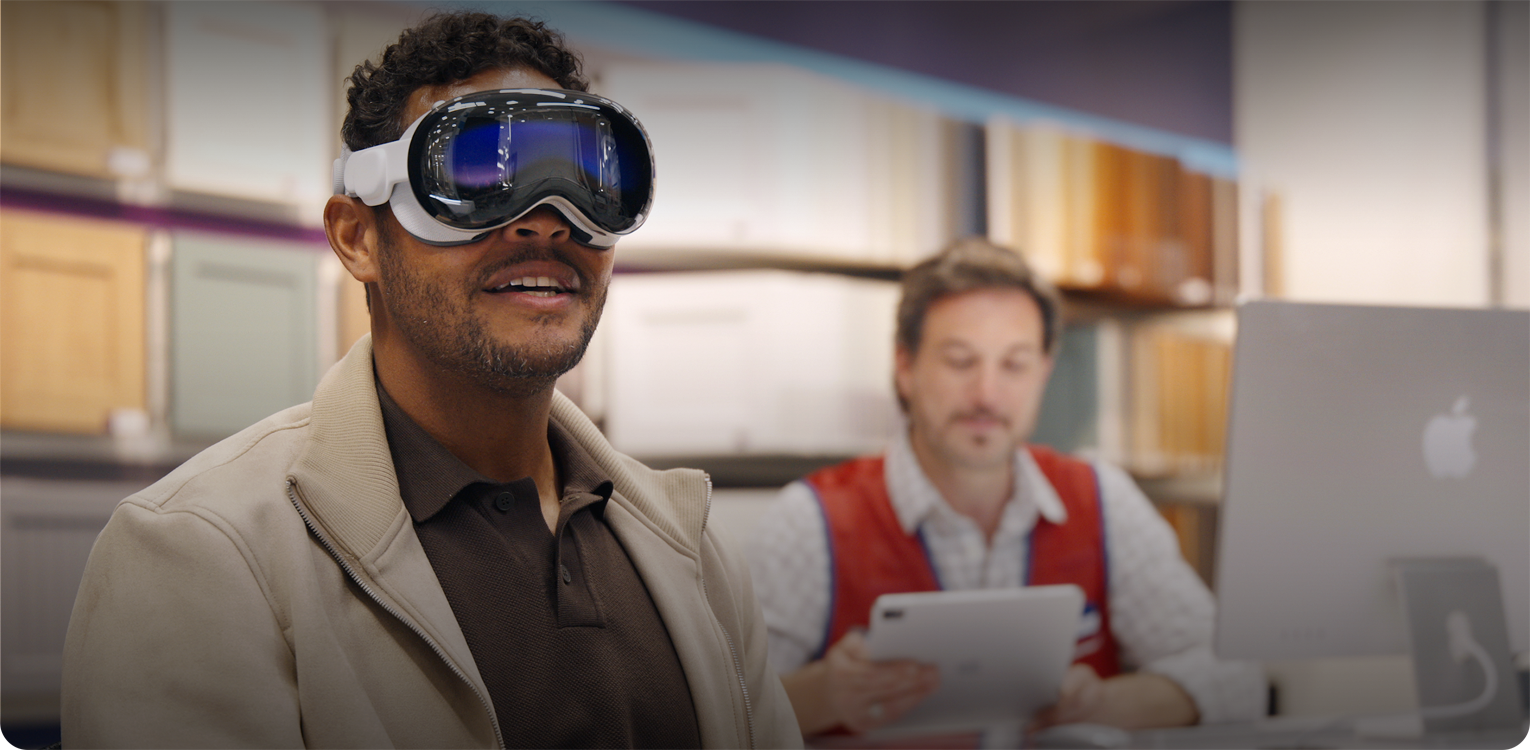 A customer in a Lowe's showroom uses Apple Vision Pro while an employee sits nearby