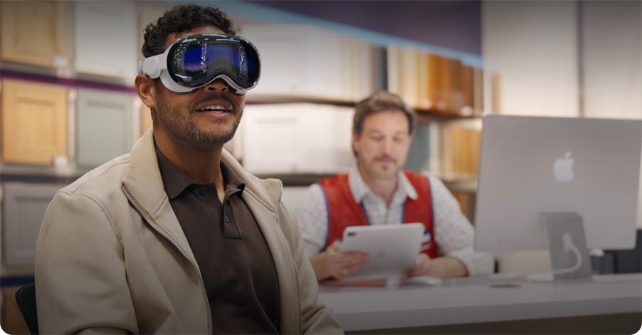 A customer in a Lowe's showroom uses Apple Vision Pro while an employee sits nearby