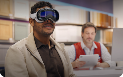 A customer in a Lowe's showroom uses Apple Vision Pro while an employee sits nearby