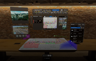 From the view of someone using Apple Vision Pro, a 3D projection of dashboards shows camera feeds, team assignments, and a map of a parade route, in front of a brick wall inside an office