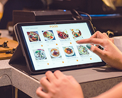 A restaurant customer using a self-service kiosk to order her meal.